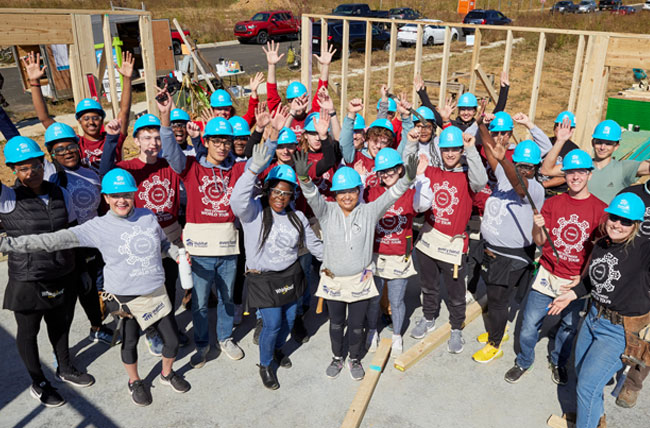 Whirlpool Corp team at the Indiana University Kelley School of Business Habitat build in 2022, taking a break from building to smile and pose with arms stretched wide.